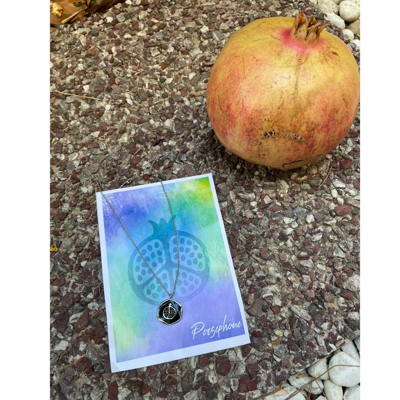 Silver pomegranate necklace inspired by Goddess Persephone on colorful background with text "Persephone"