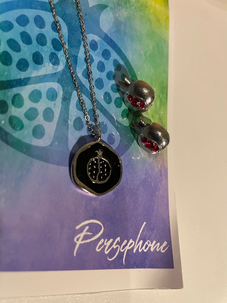 Silver pomegranate necklace inspired by Greek Goddess Persephone with colorful background.